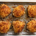 Golden oven fried chicken thighs on a wire rack over a baking sheet