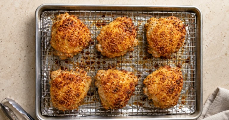 Golden oven fried chicken thighs on a wire rack over a baking sheet