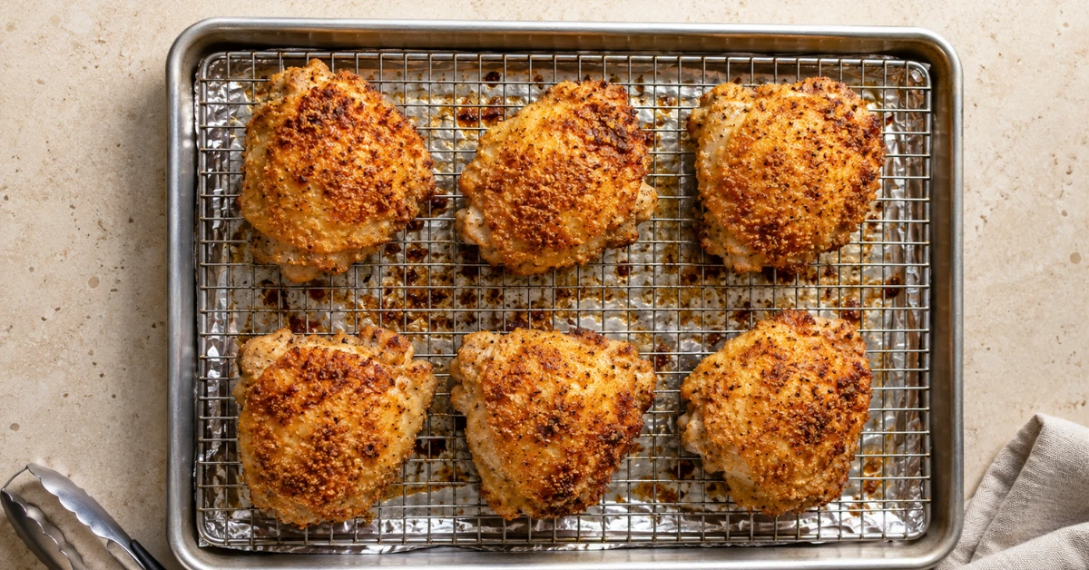 Golden oven fried chicken thighs on a wire rack over a baking sheet